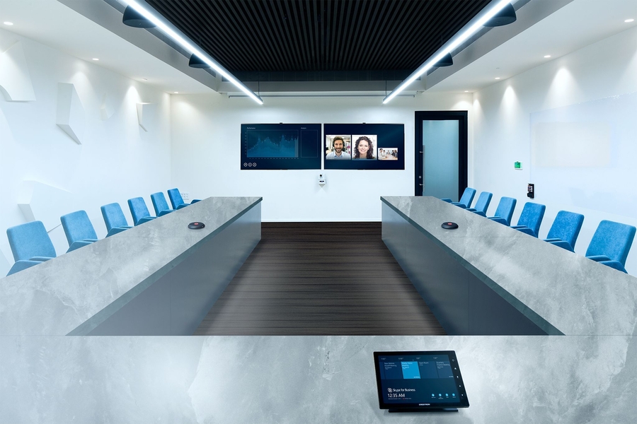 Modern meeting room with a video conference on the screen and a Crestron tablet on the table.