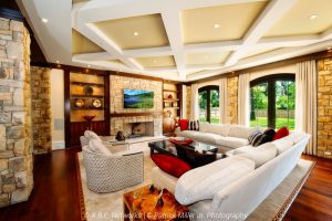 A living room with in-ceiling speakers, beautiful lighting, and a vibrant TV display above a fireplace.
