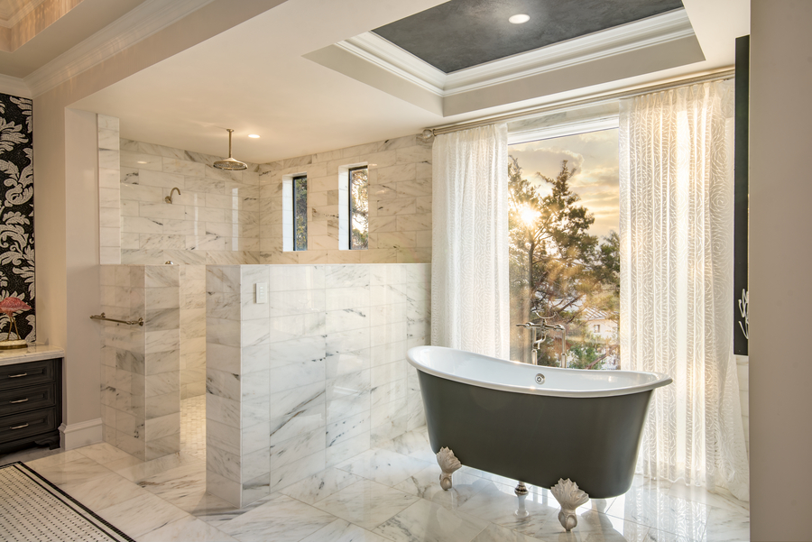 A bathroom with a claw-foot tub softly illuminated by Ketra lighting and sunlight streaming through the window.