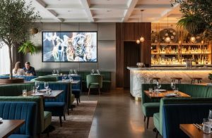 A restaurant with in-ceiling speakers and a large video wall. Social Media Blurb: Guests are no longer looking for just great food and beverages.